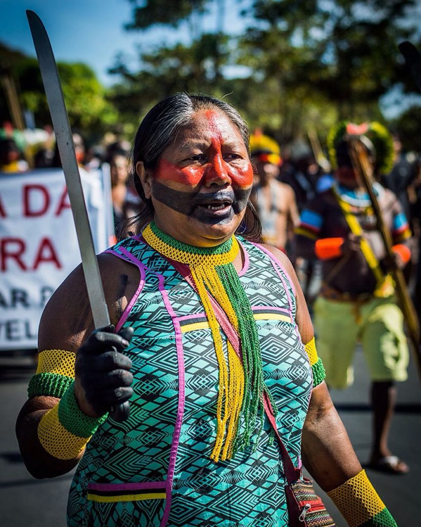 Mulher indígena com corpo pintado em manifestação