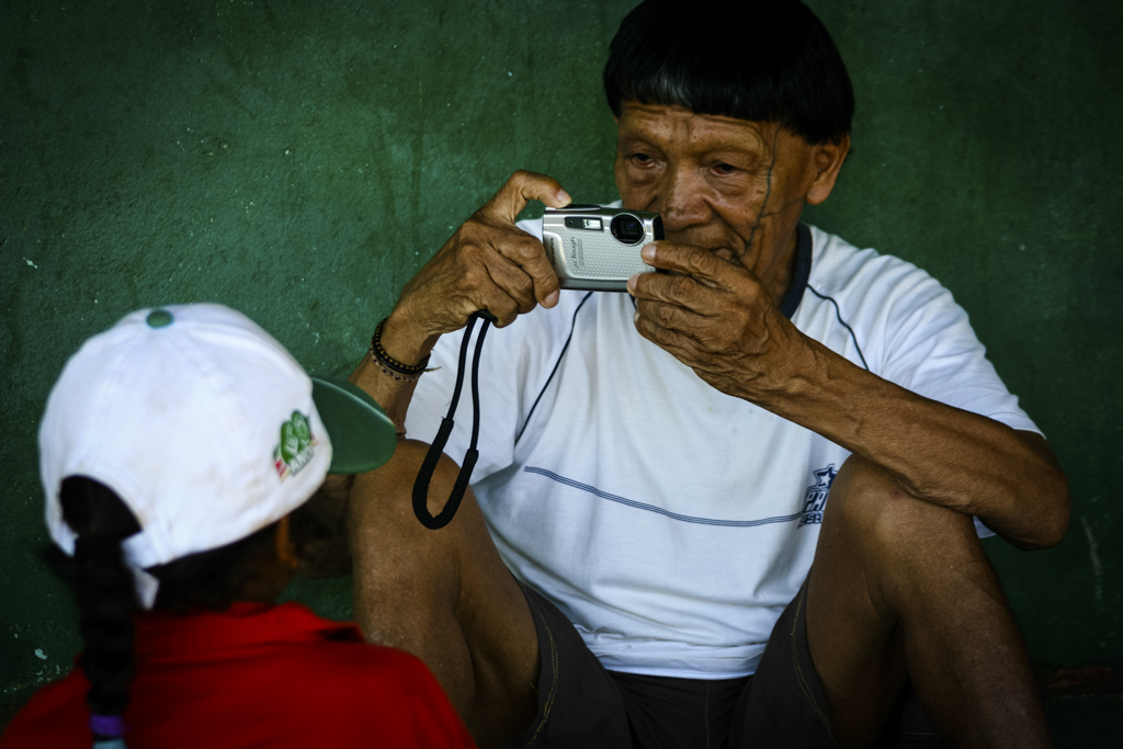 Homem indígena com uma câmera fotográfica.