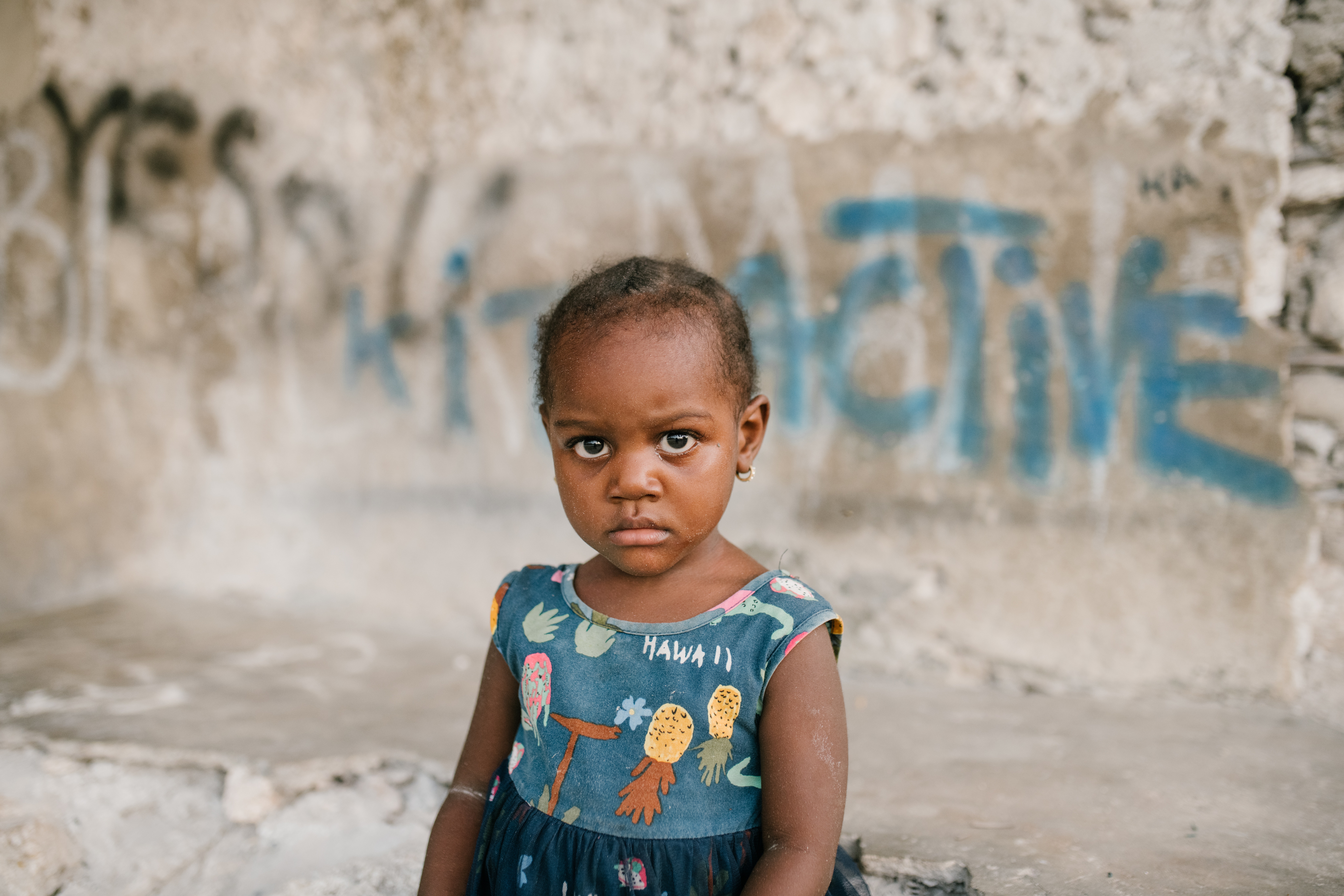 Menina negra em frente a um muro pixado, ilustrando o tema do artigo: infância, diversidade e responsabilidade